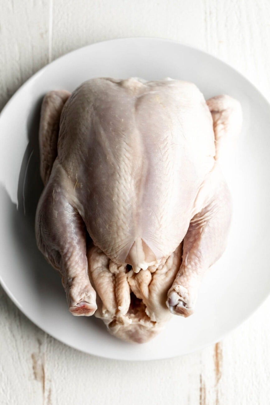 whole raw chicken on plate.