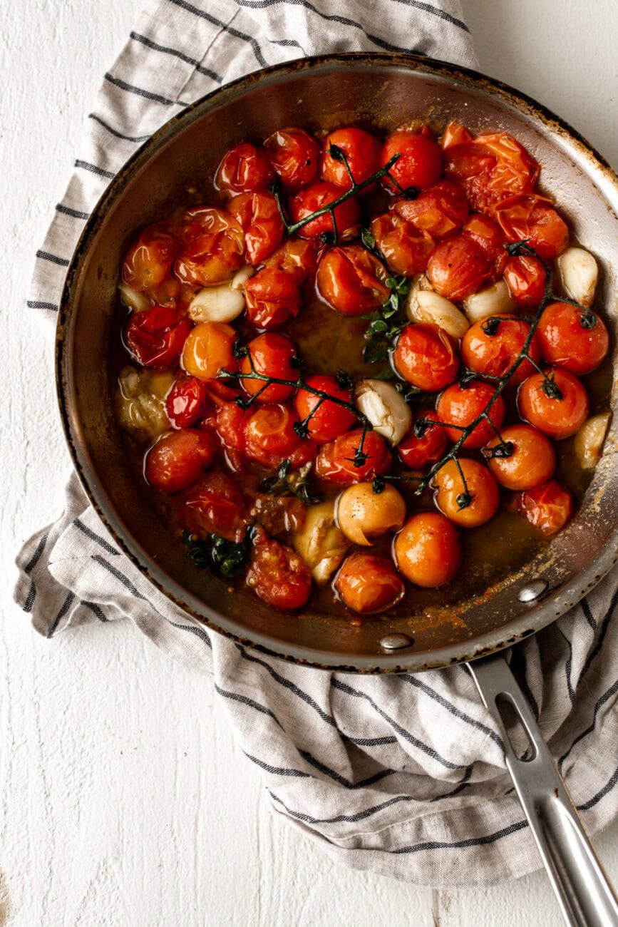 tomato confit with garlic in skillet.