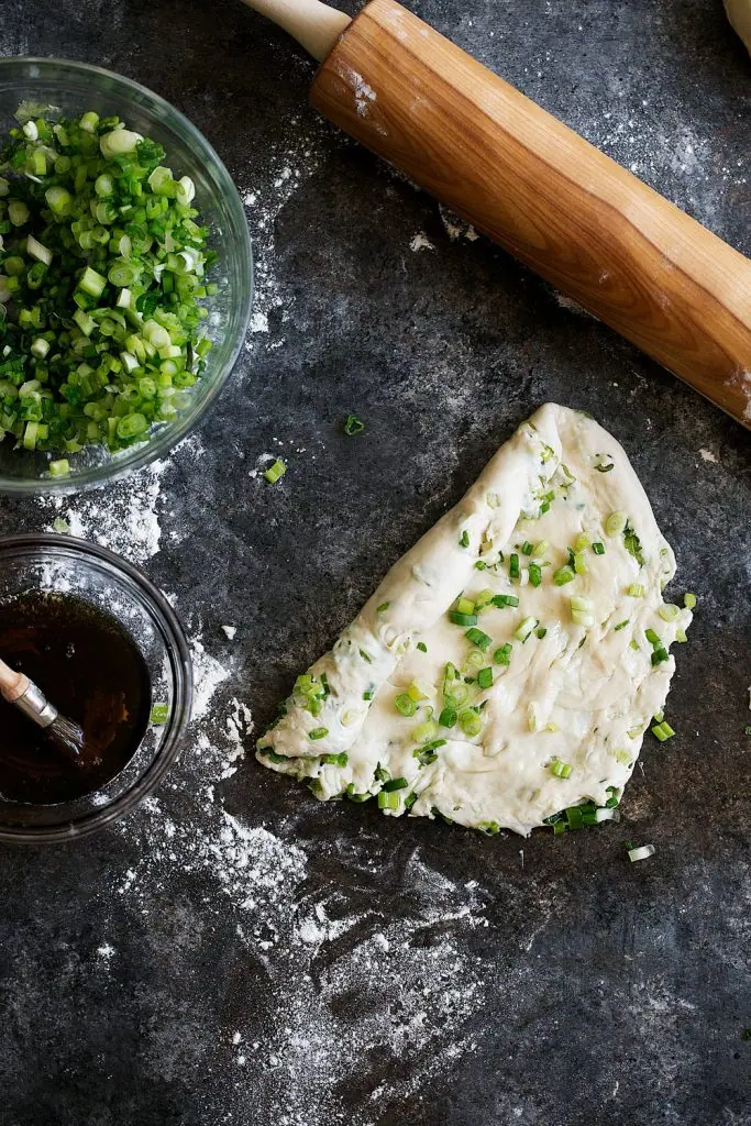 dough rolled out painted with sesame oil and topped with green onions step 6