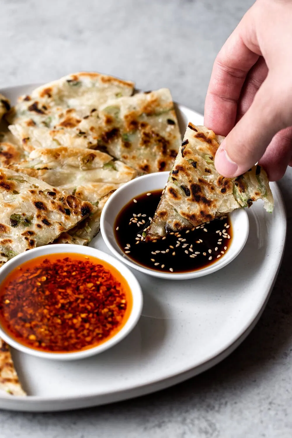 Chinese-style Scallion Pancakes cooked in a skillet dipping piece in Chinese black vinegar