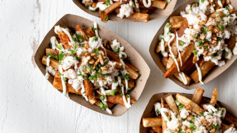 Seasoned Garlic Crab Fries with Aioli garnished with crispy garlic and diced jalapeño.