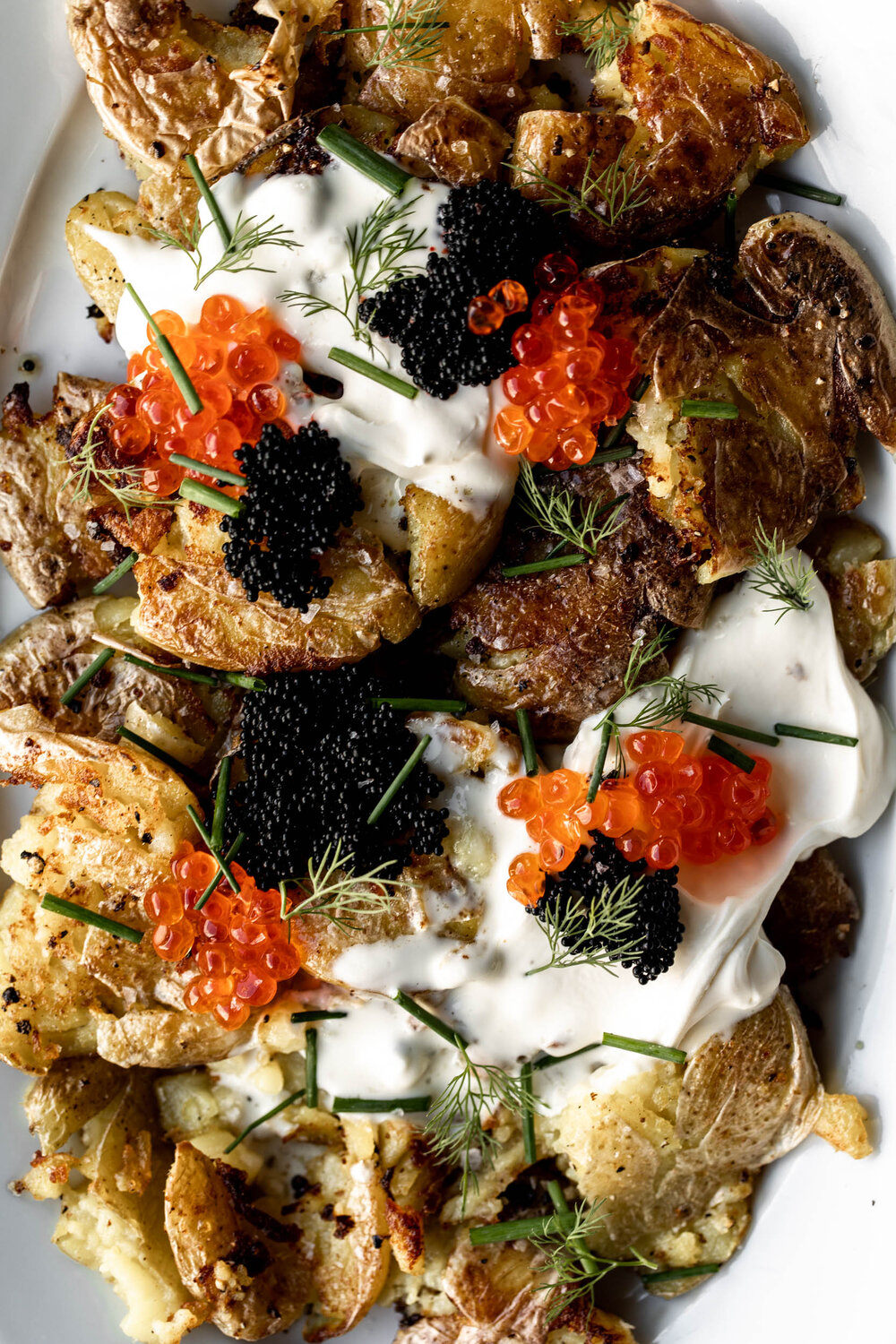 Crispy Smashed Fried Potatoes topped with creme fraiche, chives and caviar for a luxurious and indulgent holiday side closeup