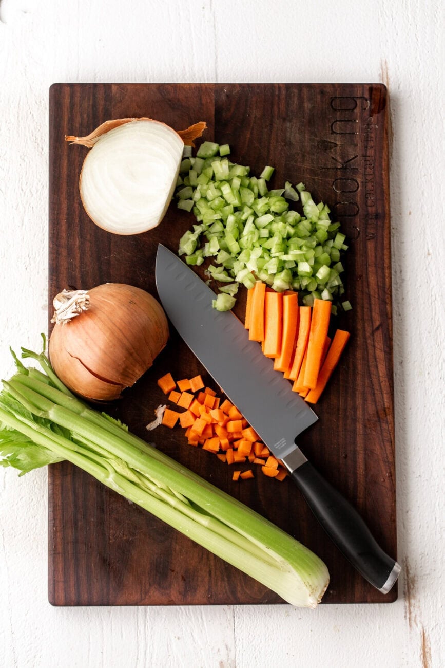 mirepoix on cutting board with chefs knife.