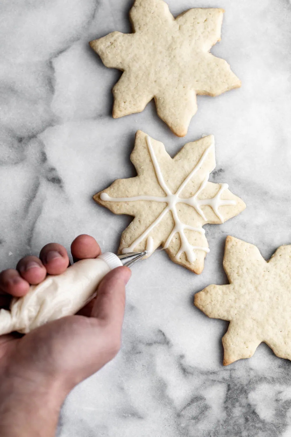 Sugar cookies in shape of snowflakes decorated with white icing 