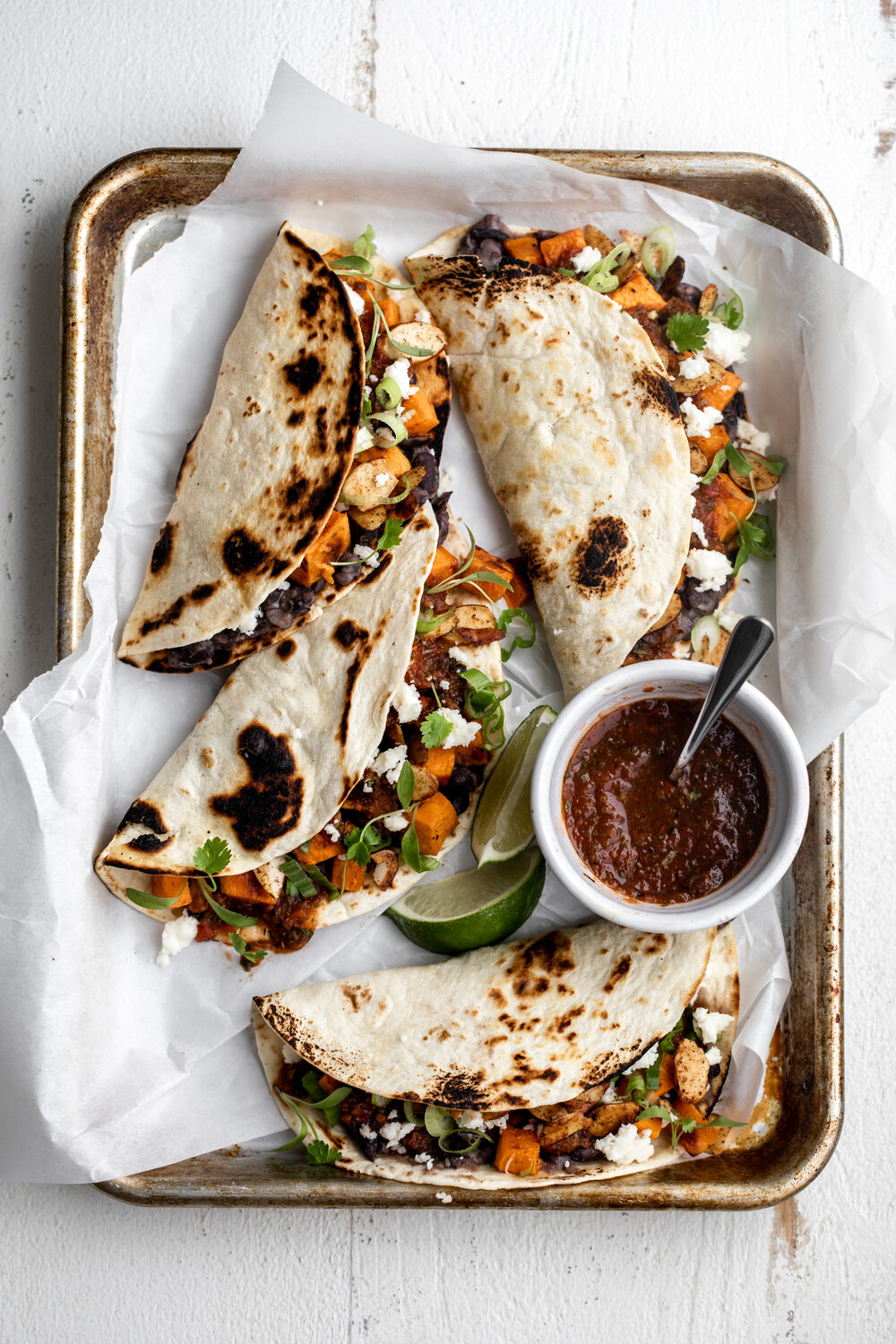 Sweet Potato and Black Bean Tacos with Chili Lime Almonds on a baking sheet with salsa