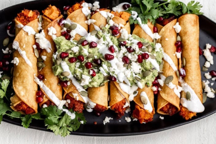 sweet potato taquitos with guacamole and pomegranate seeds.