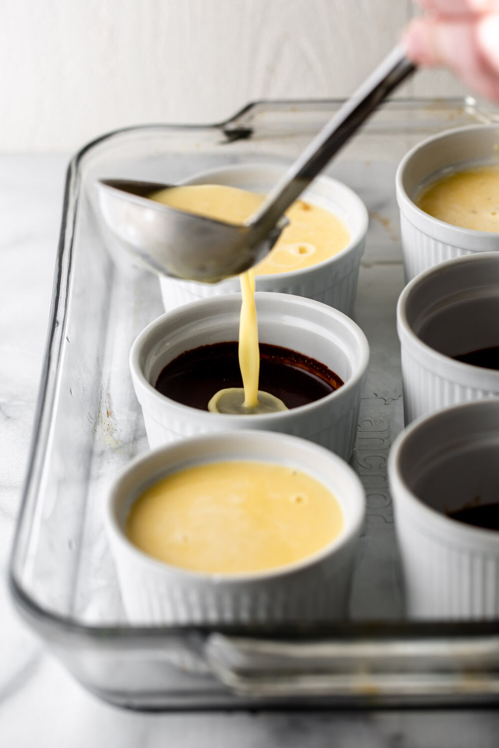 pouring creme brulee custard over chocolate ganache