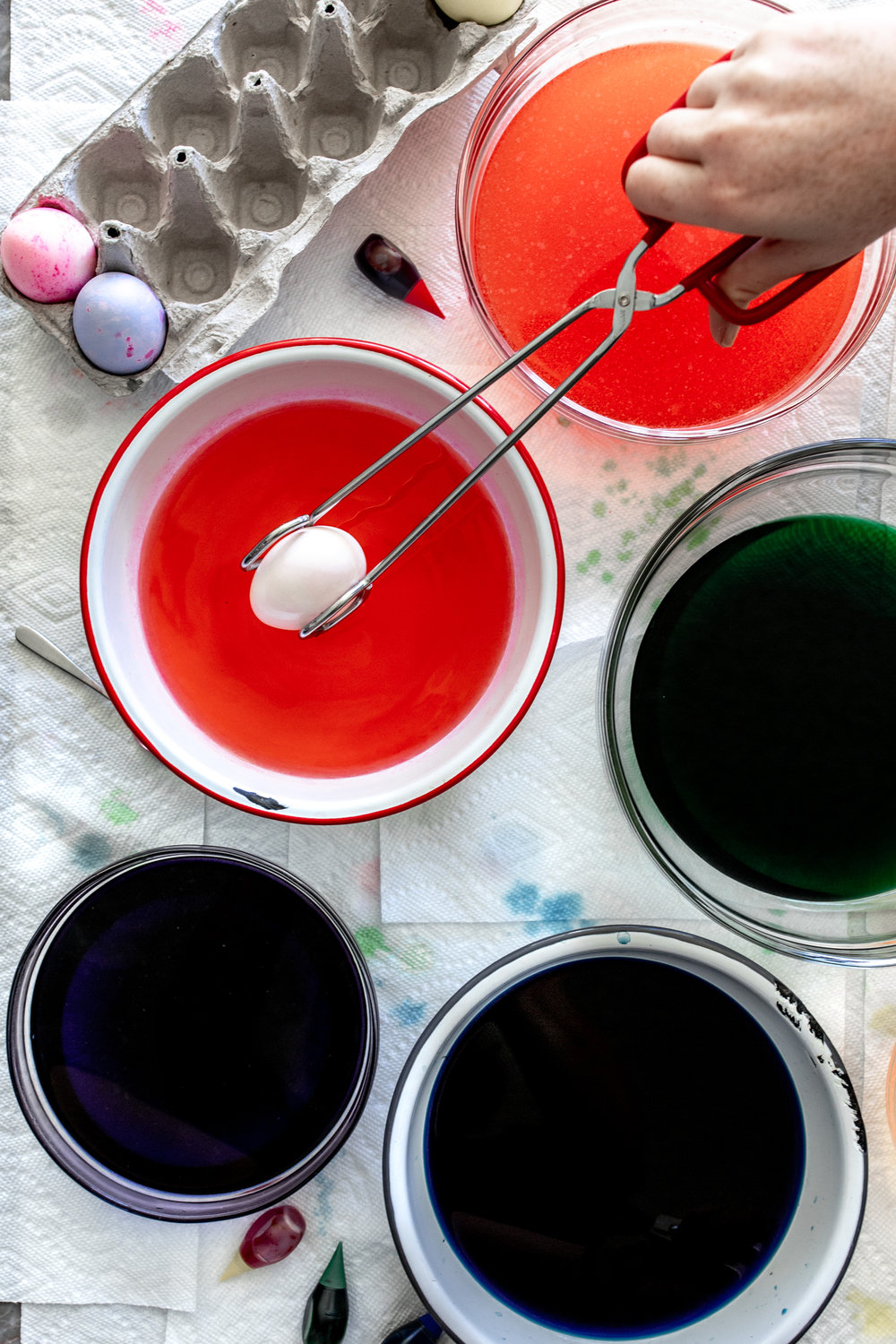 easter eggs tongs and colored bowls with water for dying eggs