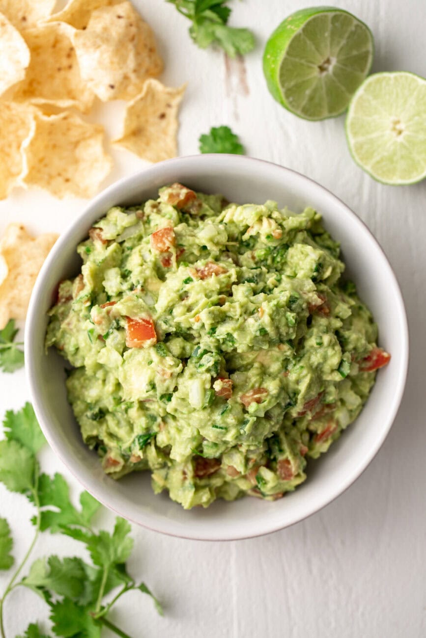 homemade guacamole with cilantro and tomatoes in bowl.