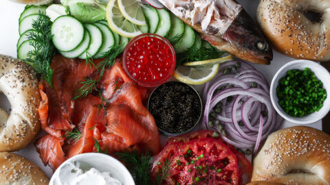 Bagel brunch ingredient shot with salmon, cream cheese, sliced onion, sliced cucumber, heirloom tomatoes, salmon roe and sturgeon caviar.