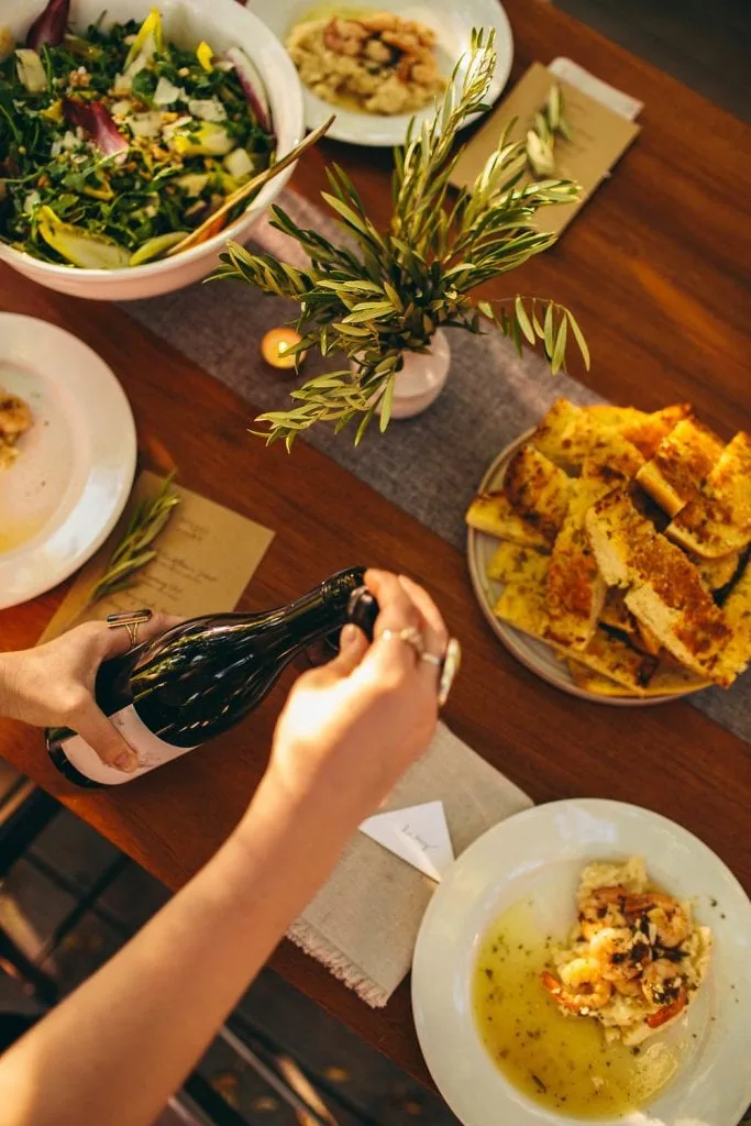 top view of food and a woman pouring wine for The South of Italy