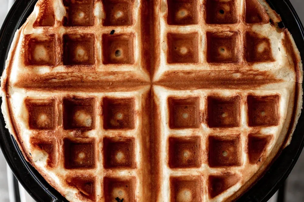 closeup waffle cooking in waffle iron