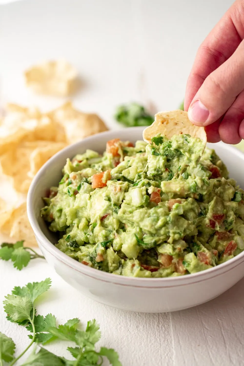 The Best Guacamole Recipe in serving bowl dipping tortilla chips