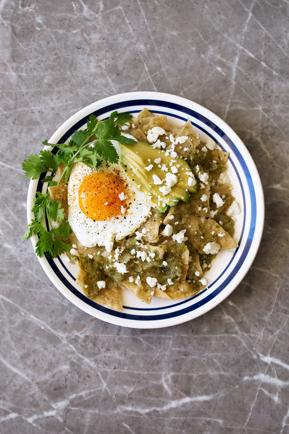 chilaquiles verdes with a fried egg recipe and avocado garnished with queso fresco