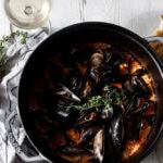 Steamed Mussels in Saffron Chorizo Broth with thyme in Dutch oven.