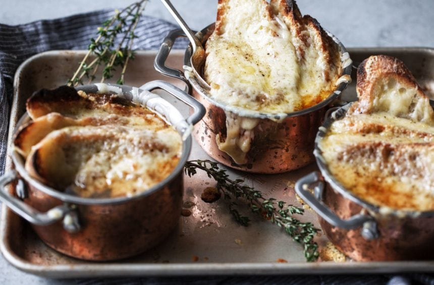 French onion soup with bread and gruyere in copper pots.