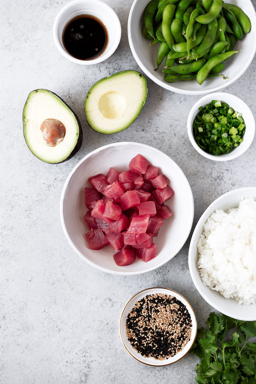 poke ingredients in bowls ahi tuna edamame in pods soy sauce white rice and halved avocado