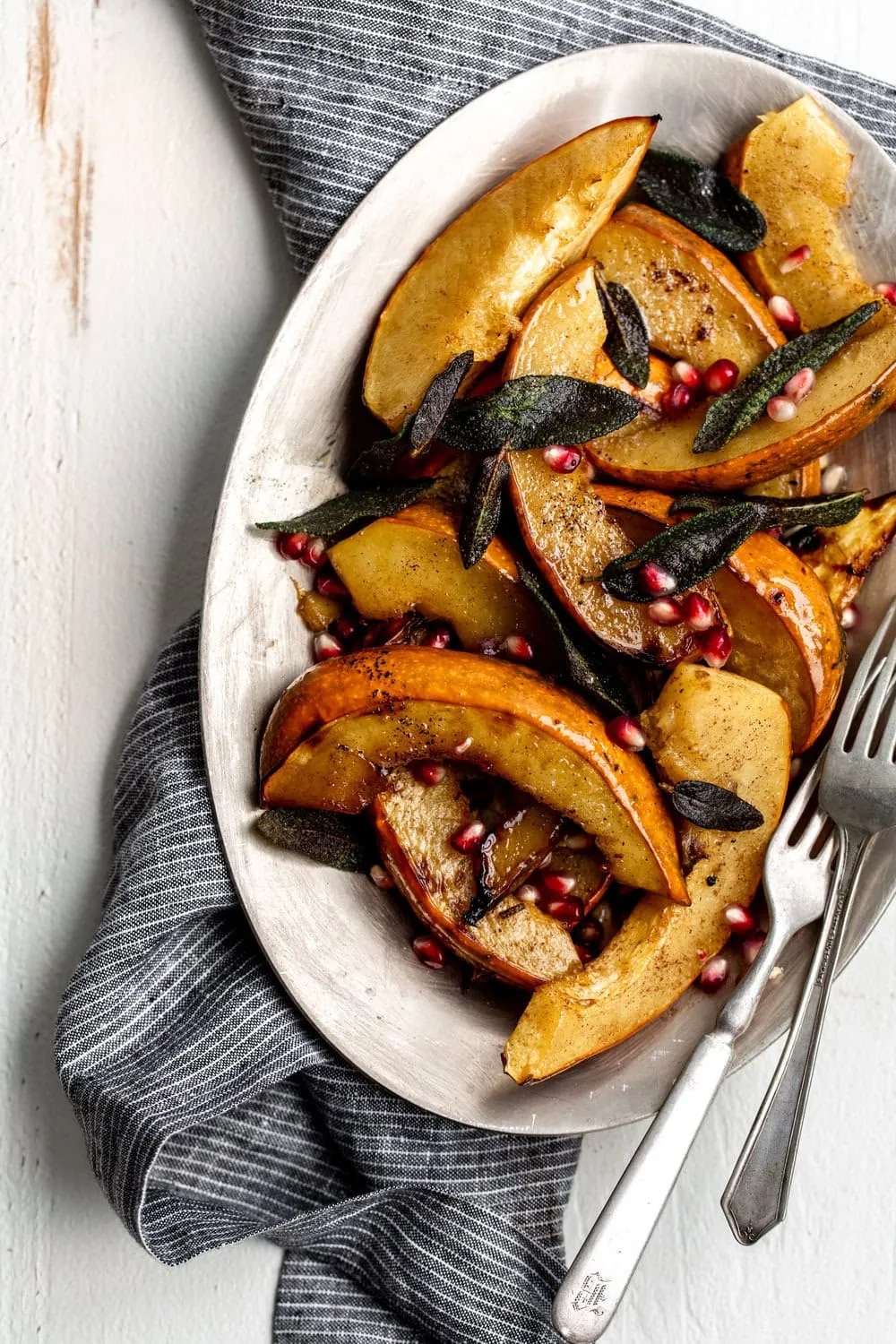 Roasted Acorn Squash with Sage recipe and pomegranate seeds on silver platter