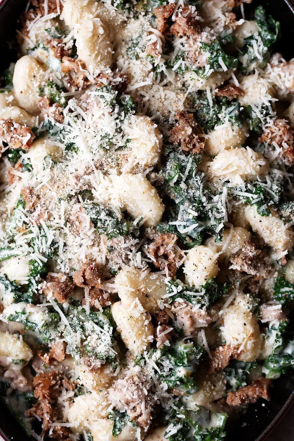 sausage and kale gnocchi with garlic cream sauce in baking dish