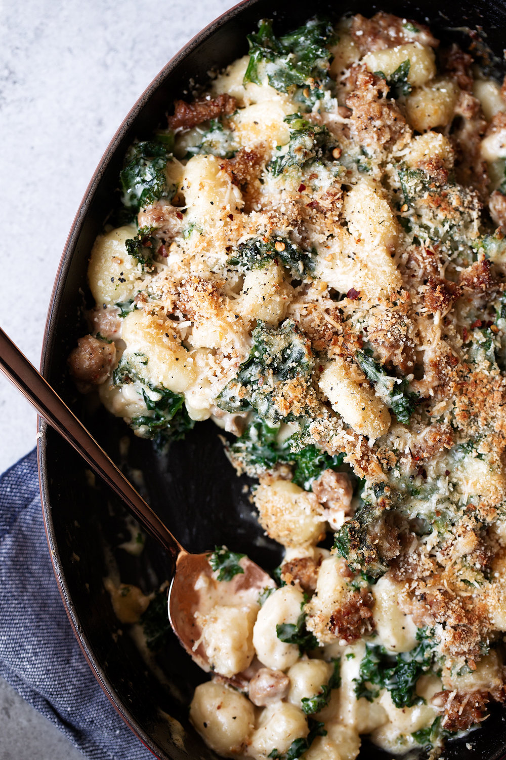 baked sausage and kale gnocchi with garlic cream sauce with serving spoon