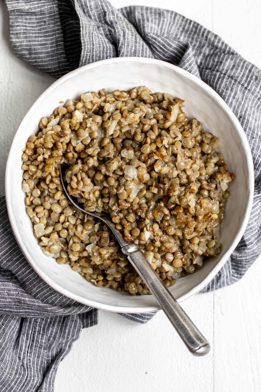 refried lentils recipe in white bowl with serving spoon