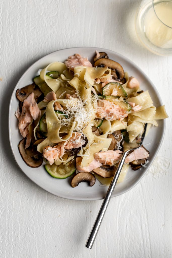 salmon and zucchini mushroom pasta on plate with fork