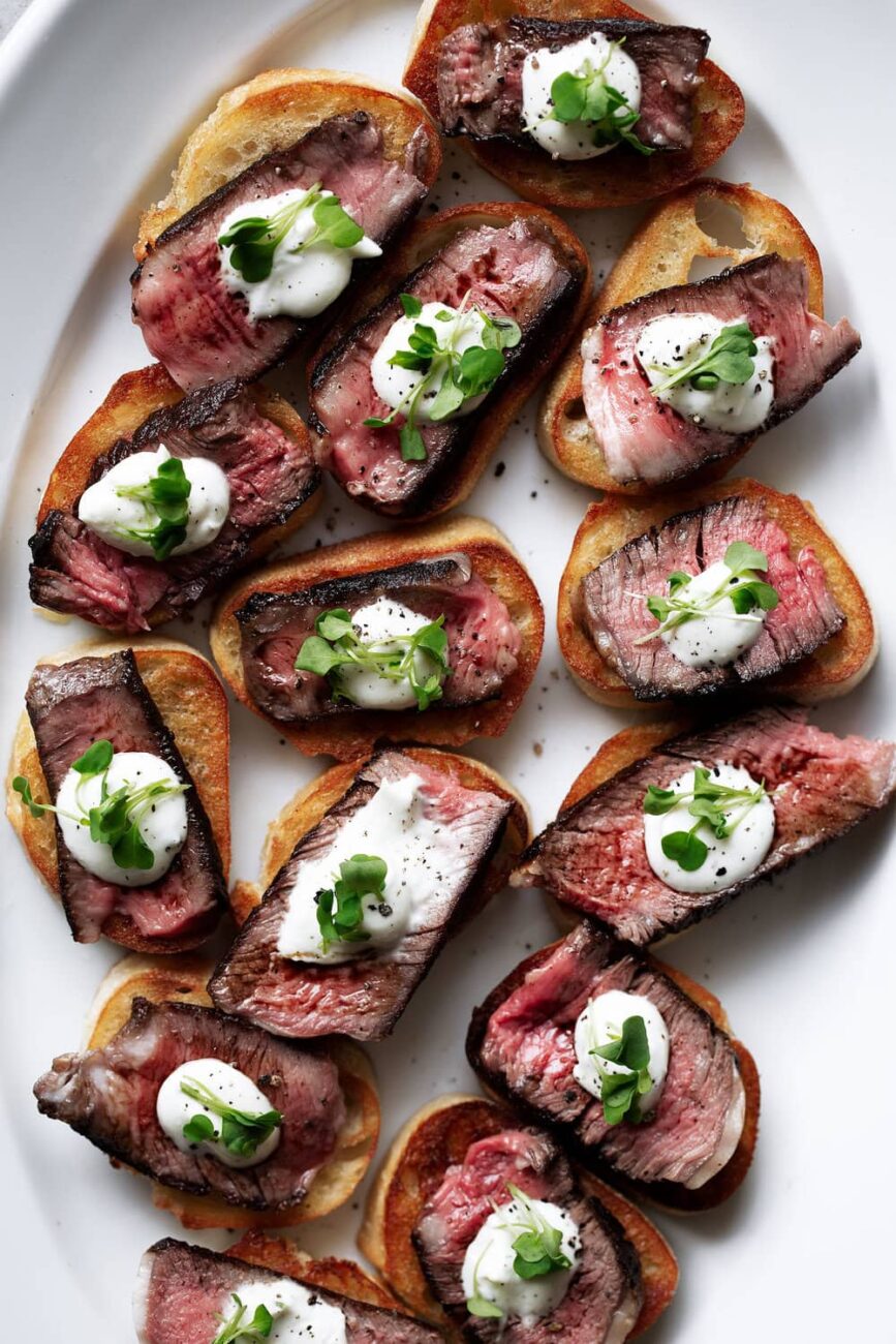 grilled ribeye steak and boursin cheese crostini recipe garnished with microgreens.