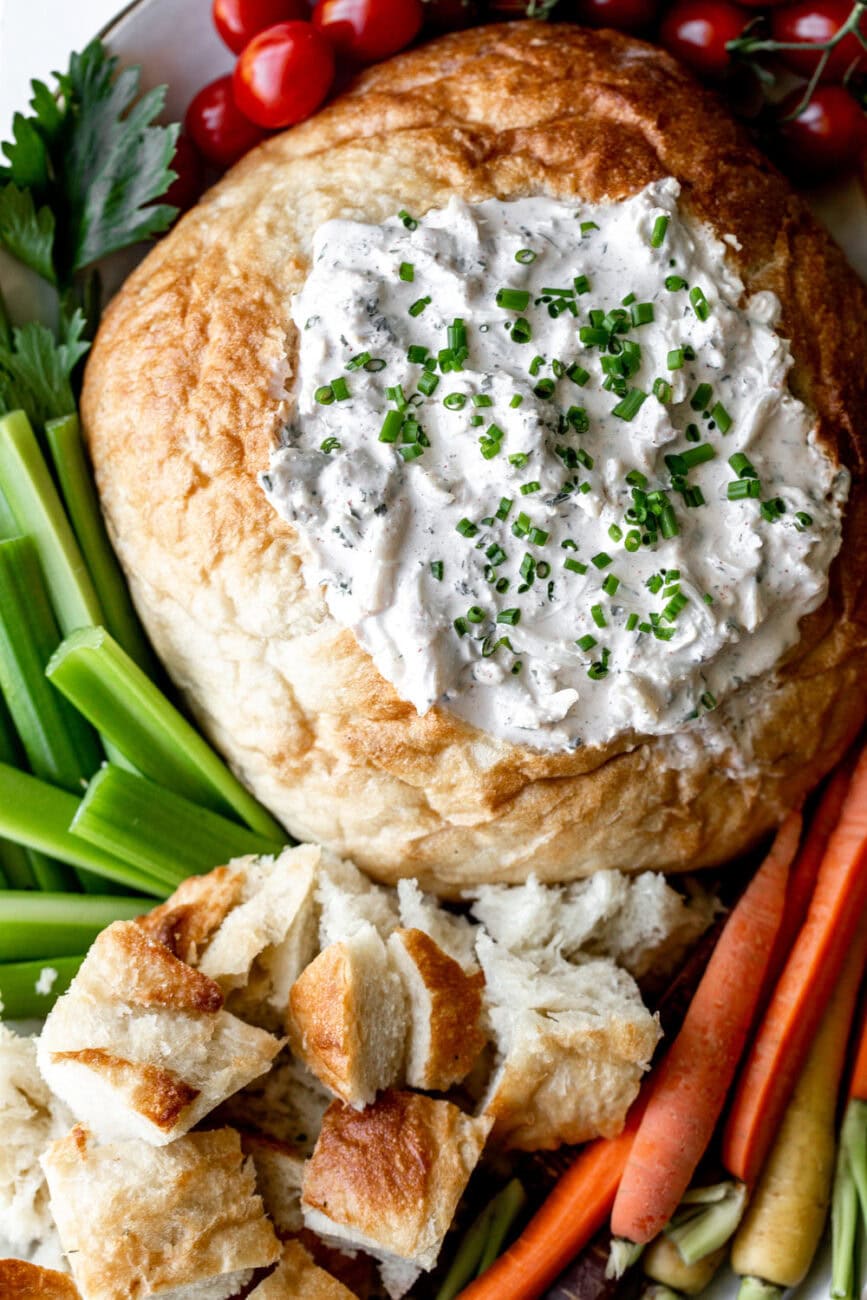 Chilled Crab Dip in a Bread Bowl with celery and carrots.