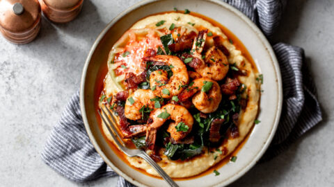 Cajun shrimp served over cheesy grits with bacon-braised collard greens.