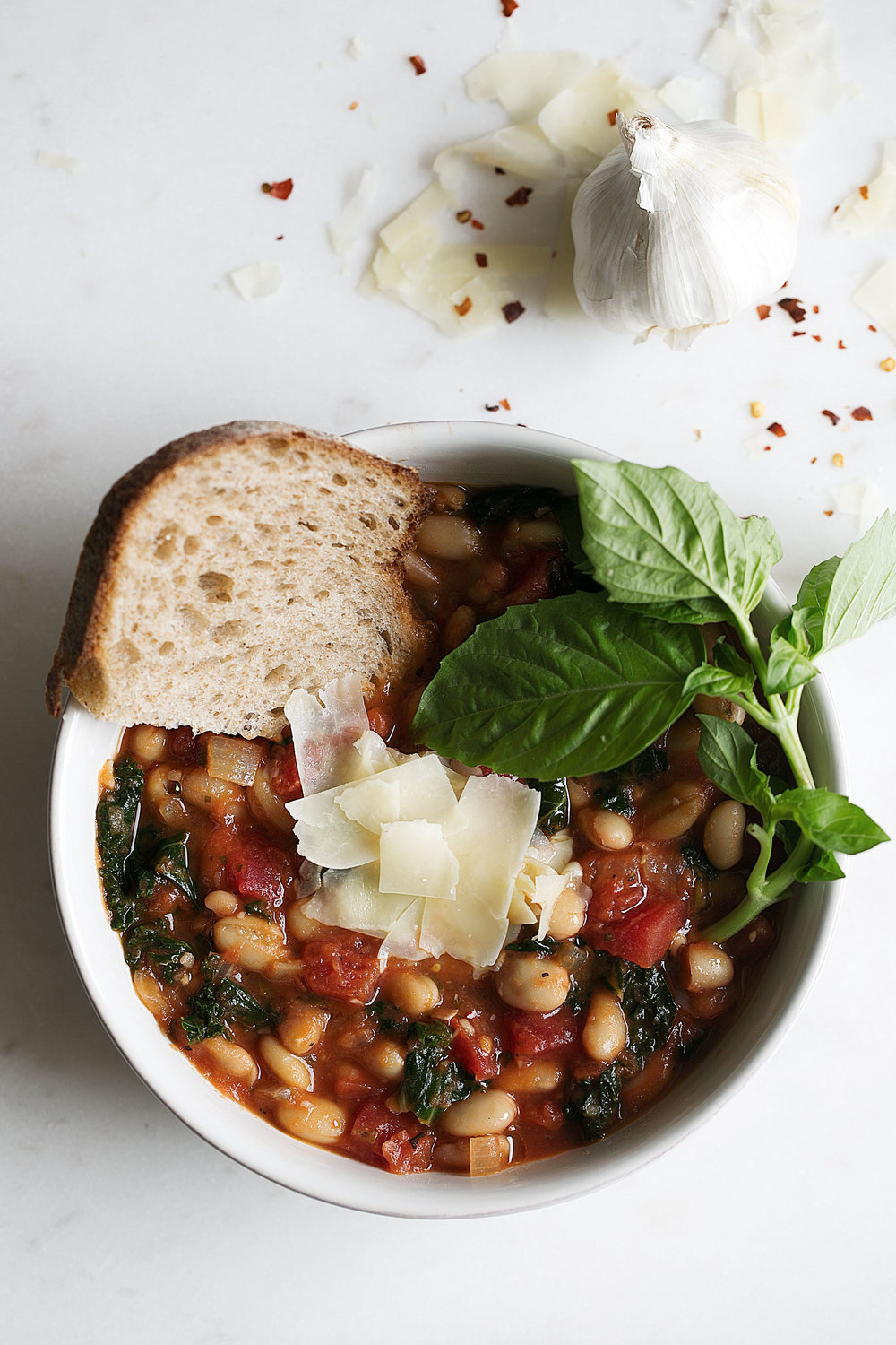 white bean and kale soup with bread and basil leaves