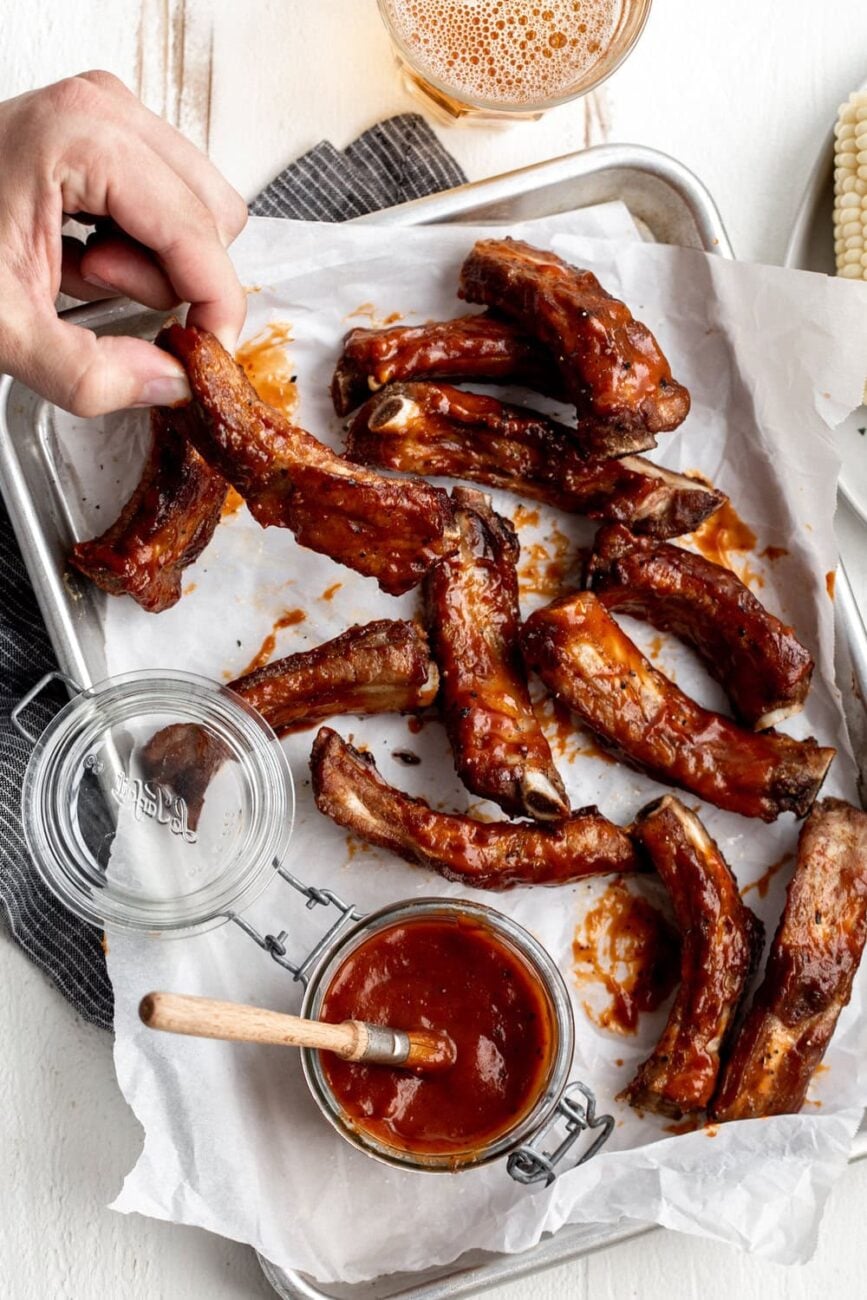 Fried Ribs with Chipotle-Peach BBQ Sauce recipe on aluminum baking tray on parchment paper.