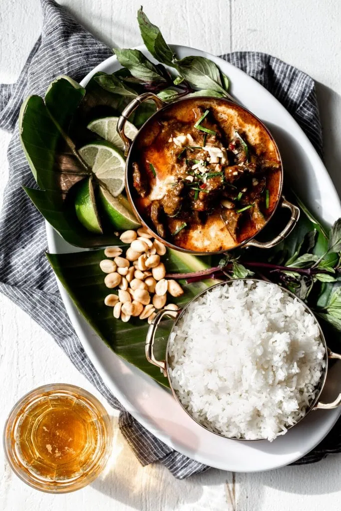 beef panang curry in bowl with steamed white rice and side of peanuts.