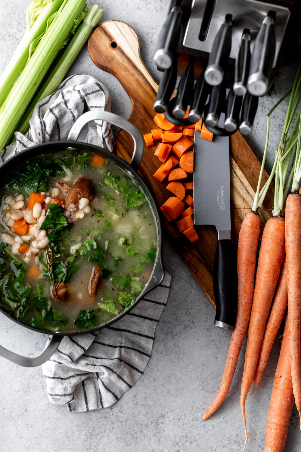 Ham Hock & White Bean Stew with Collard Greens with knives and carrots on cutting board