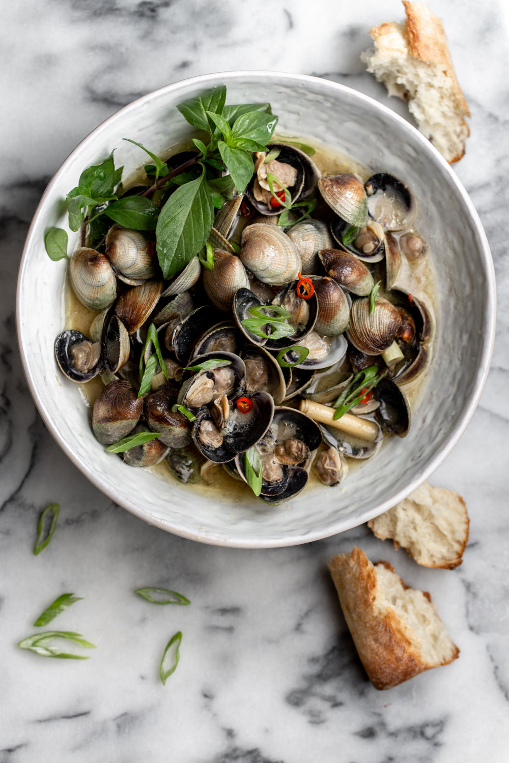 thai lemongrass coconut clams recipe with thai basil in white bowl with bread 