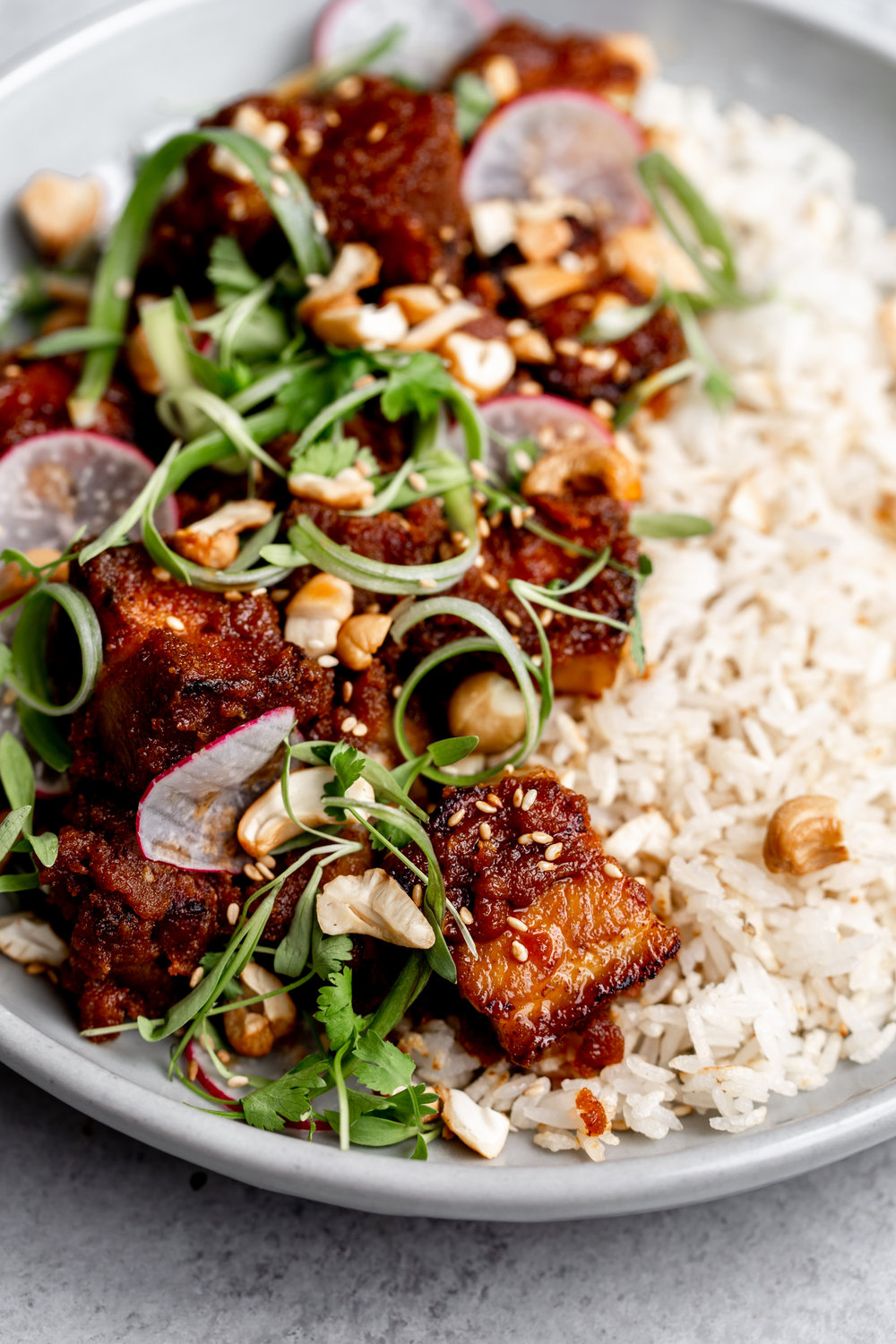 Roasted pork belly tossed in gochujang and cashew butter sauce a over crispy rice with cilantro and cashews