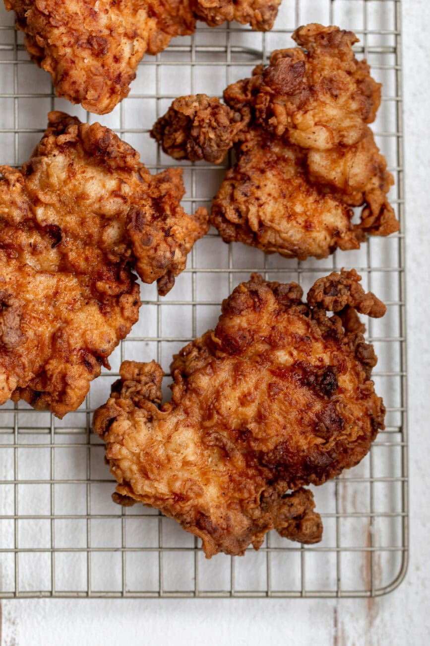 Fried boneless chicken thighs on baking rack.