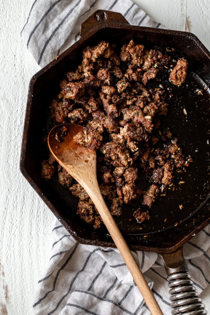lamb merguez sausage in cast iron pan.