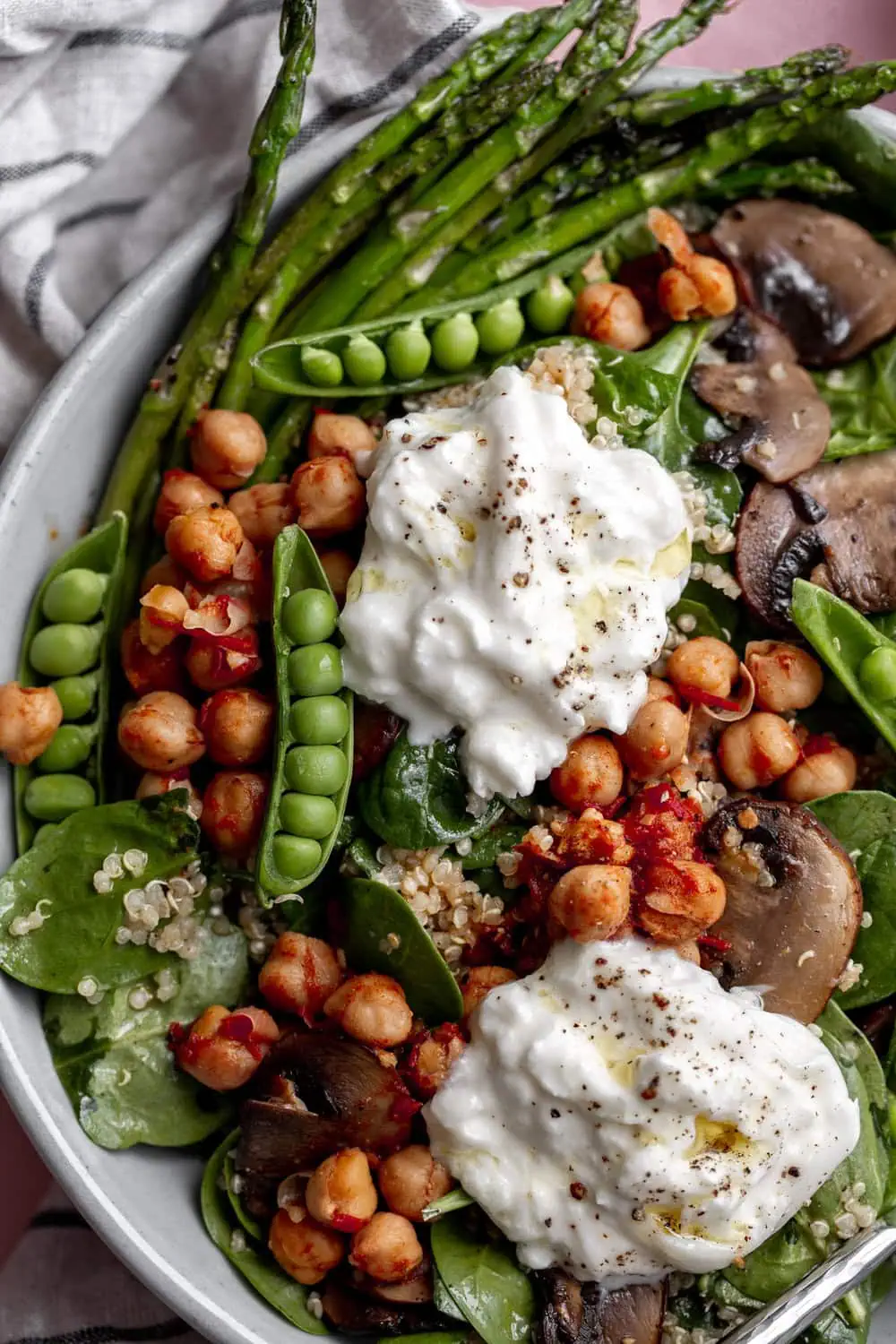 Spinach served with quinoa and harissa spiced chickpeas tossed in carrot-orange vinaigrette with sautéed vegetables topped with burrata.