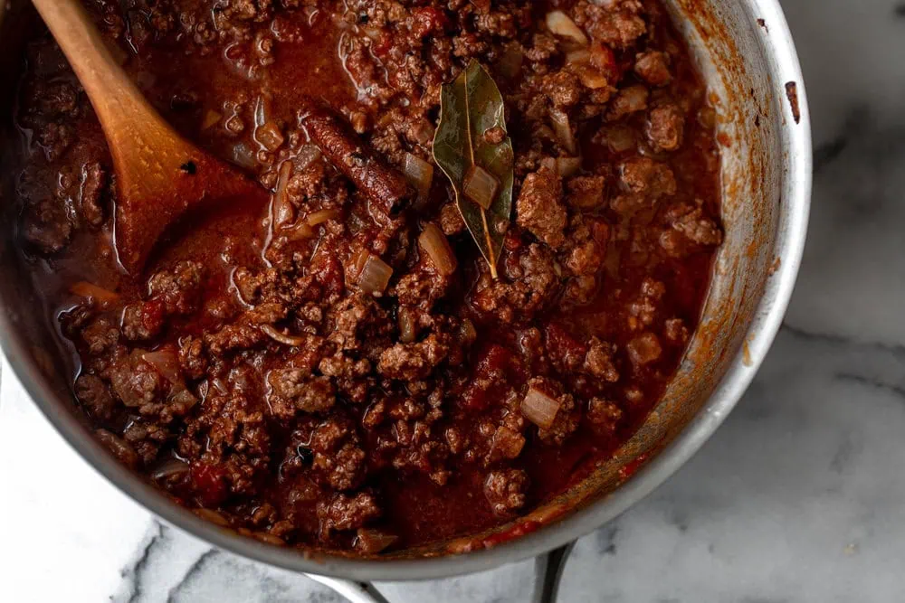Greek Moussaka meat sauce in pan with bay leaf and cinnamon