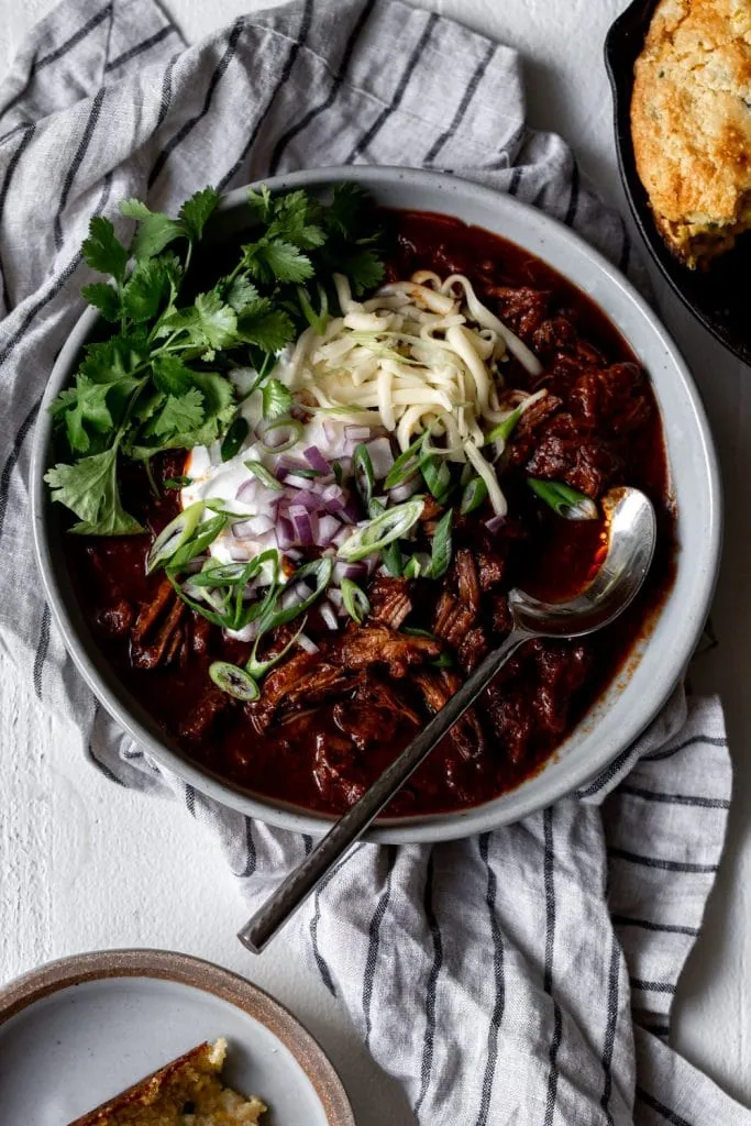 Texas-Style Beef Short Rib Chili with Monterey jack cheese and spoon.