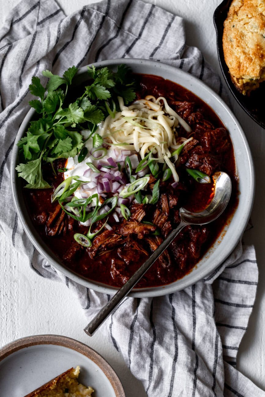 Texas-Style Beef Short Rib Chili with a side of cornbread topped with cheese and cilantro.