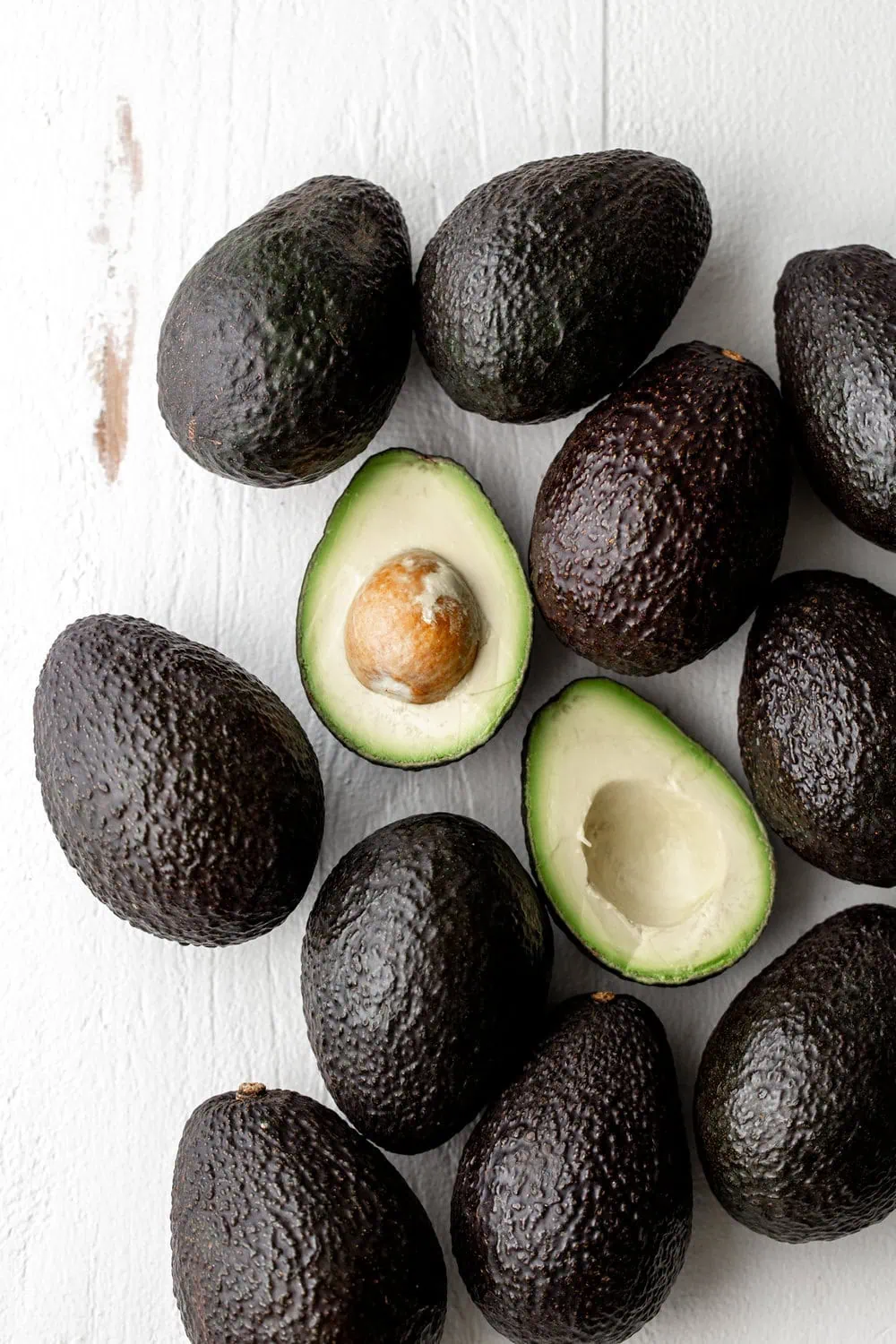 california avocados halved on white wood background 
