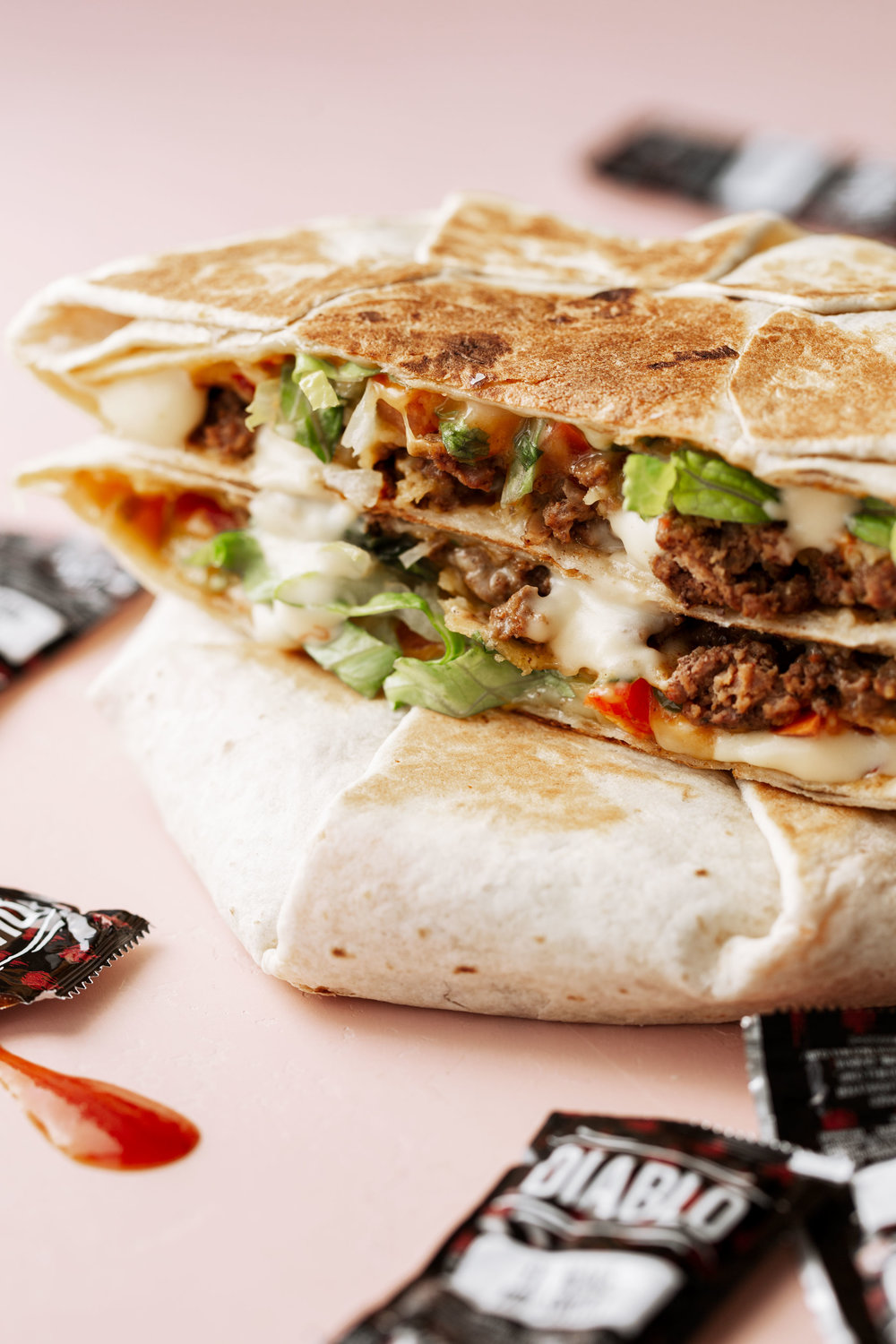 homemade crunch wrap supreme recipe stacked layers of tortillas, spiced ground beef, cheese sauce, lettuce and tomato