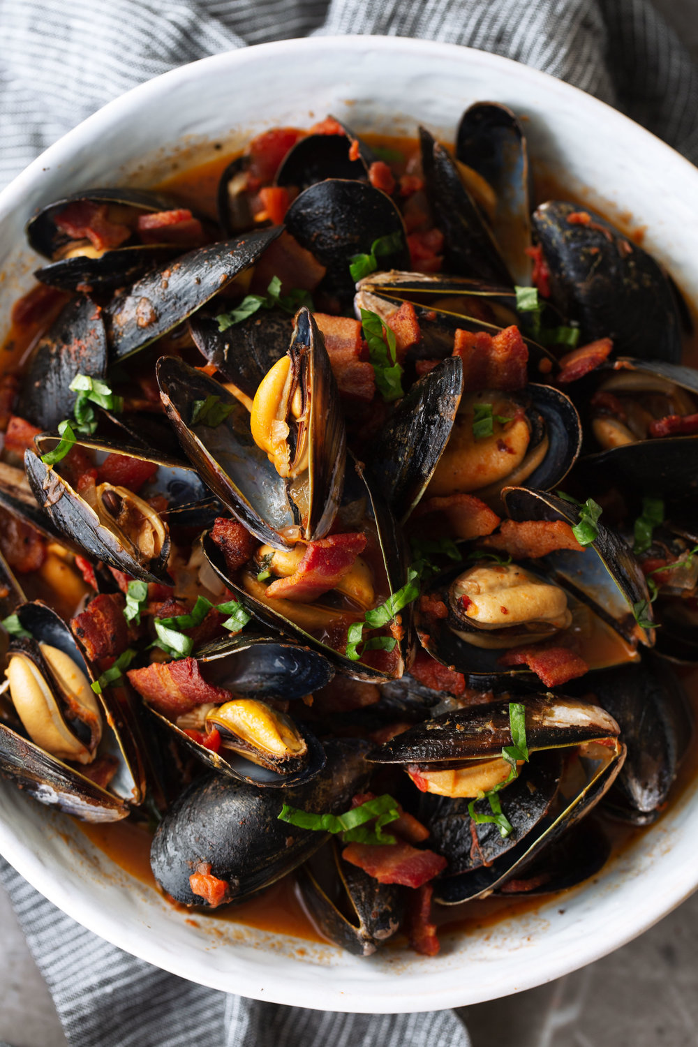 mussels in tomato broth with bacon garnished with parsley
