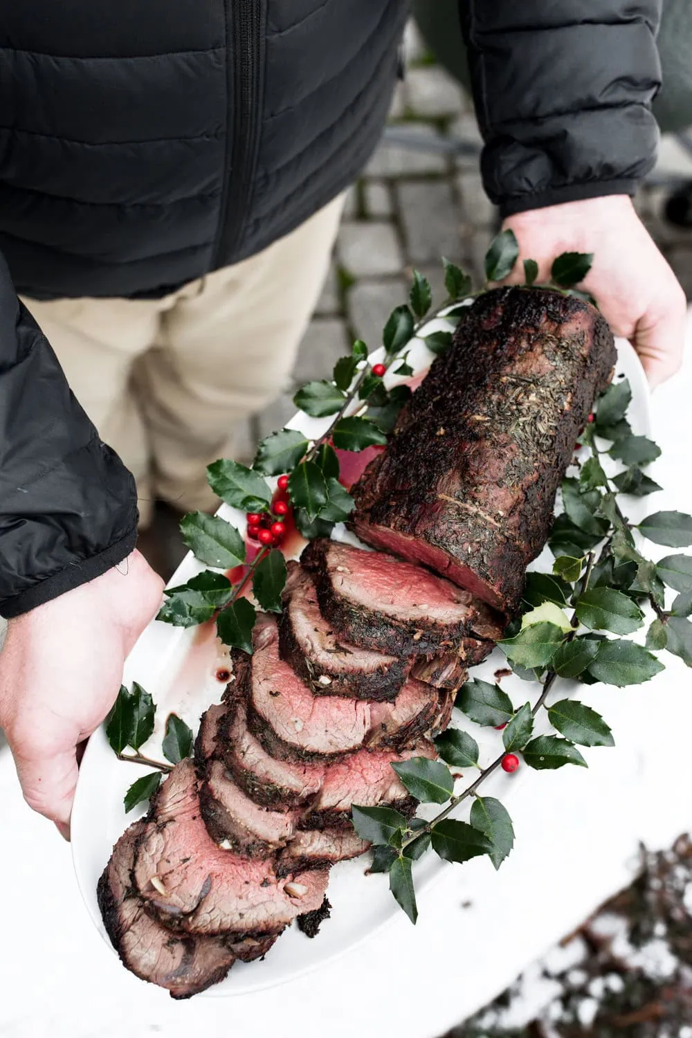 Herb Roast Beef Tenderloin recipe with herb exterior garnished with holly on white platter