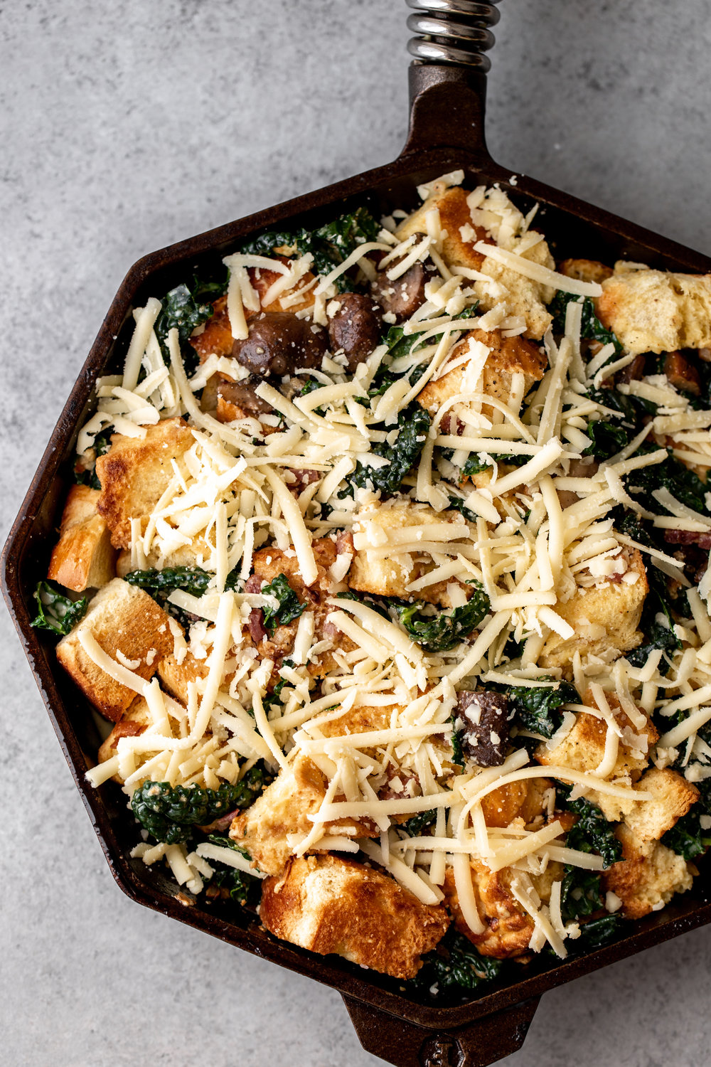 Cheesy Mushroom and Kale Brioche Strata with Pancetta assembled in cast iron pan