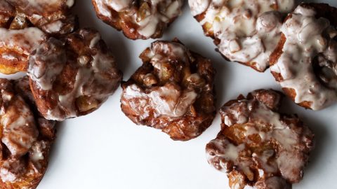 cider glazed apple fritters arranged on a white background