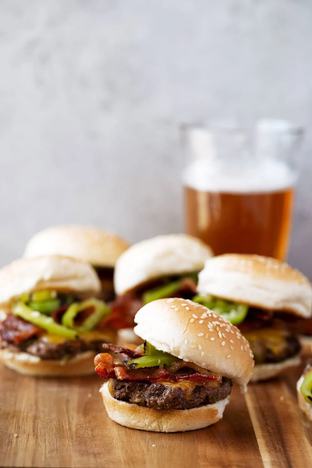 Hatch chilies are blistered and served with cheddar cheese and bacon on smash ground beef patty sliders on seeded buns