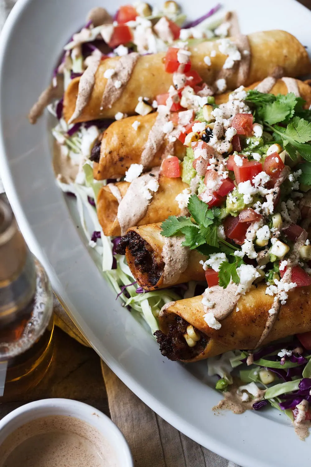 chicken flautas with mushroom and roasted corn with chipotle mayonnaise topped with guacamole diced tomatoes and cilantro