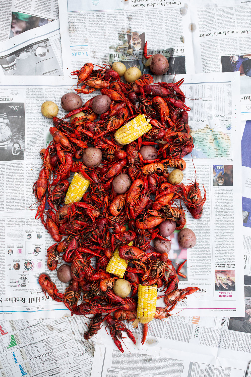 traditional southern crawfish boil recipe with corn and potatoes spread on newspaper